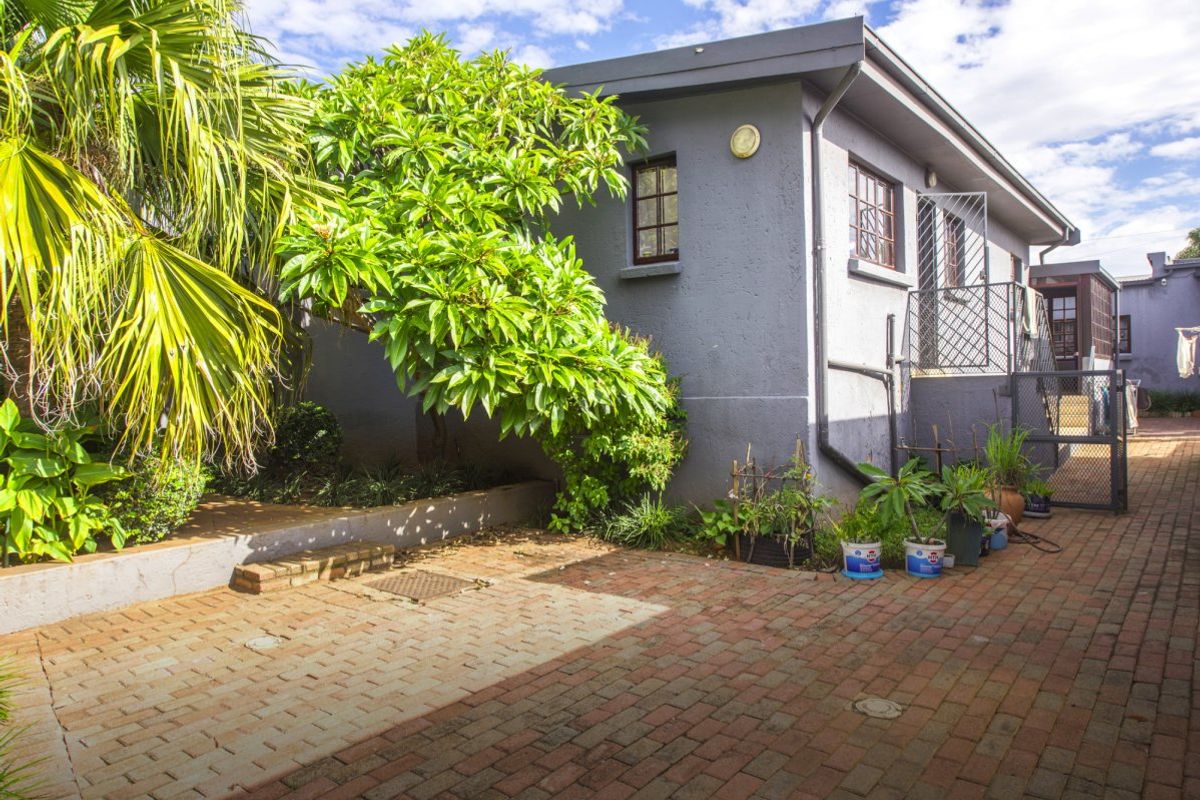 A view of the rear exterior area featuring brick paving, a retaining wall, and a secure side entrance to the property.
