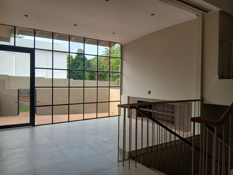 Spacious living area featuring large steel-framed windows, tiled flooring, and a built-in cabinet, offering a bright and modern open-plan feel.
