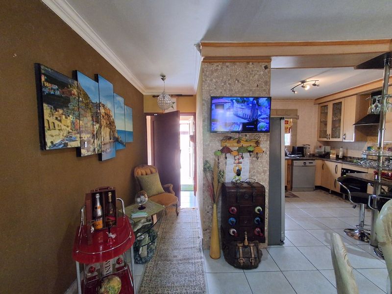 Open plan living area featuring tiled flooring, a kitchen with built-in cabinetry and appliances, and a decorative stone-tiled feature pillar.