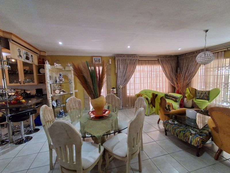 Spacious open-plan living and dining area featuring tiled flooring, recessed lighting, and an integrated kitchen with granite countertops.