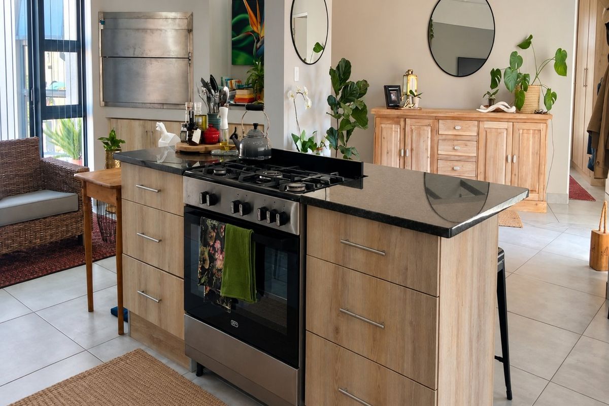 Modern kitchen featuring a central island with a gas stove, granite countertops, and a built-in braai, set within an open-plan living space.