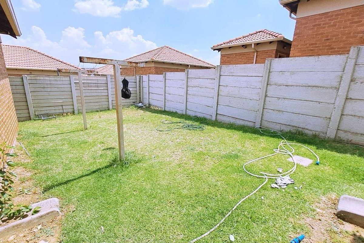 A private rear garden area enclosed by precast concrete boundary walls, featuring a lawn and a fixed metal washing line structure.