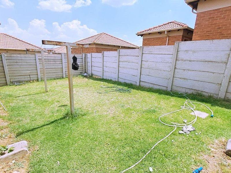 A private rear garden area enclosed by precast concrete boundary walls, featuring a lawn and a fixed metal washing line structure.
