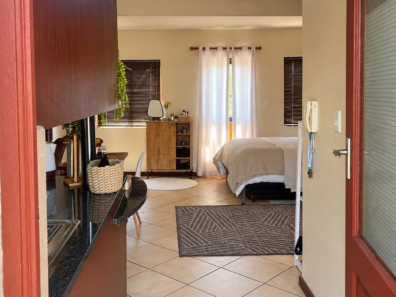 Open-plan apartment layout featuring a kitchen with granite countertops and tiled flooring, seamlessly flowing into the bedroom area.