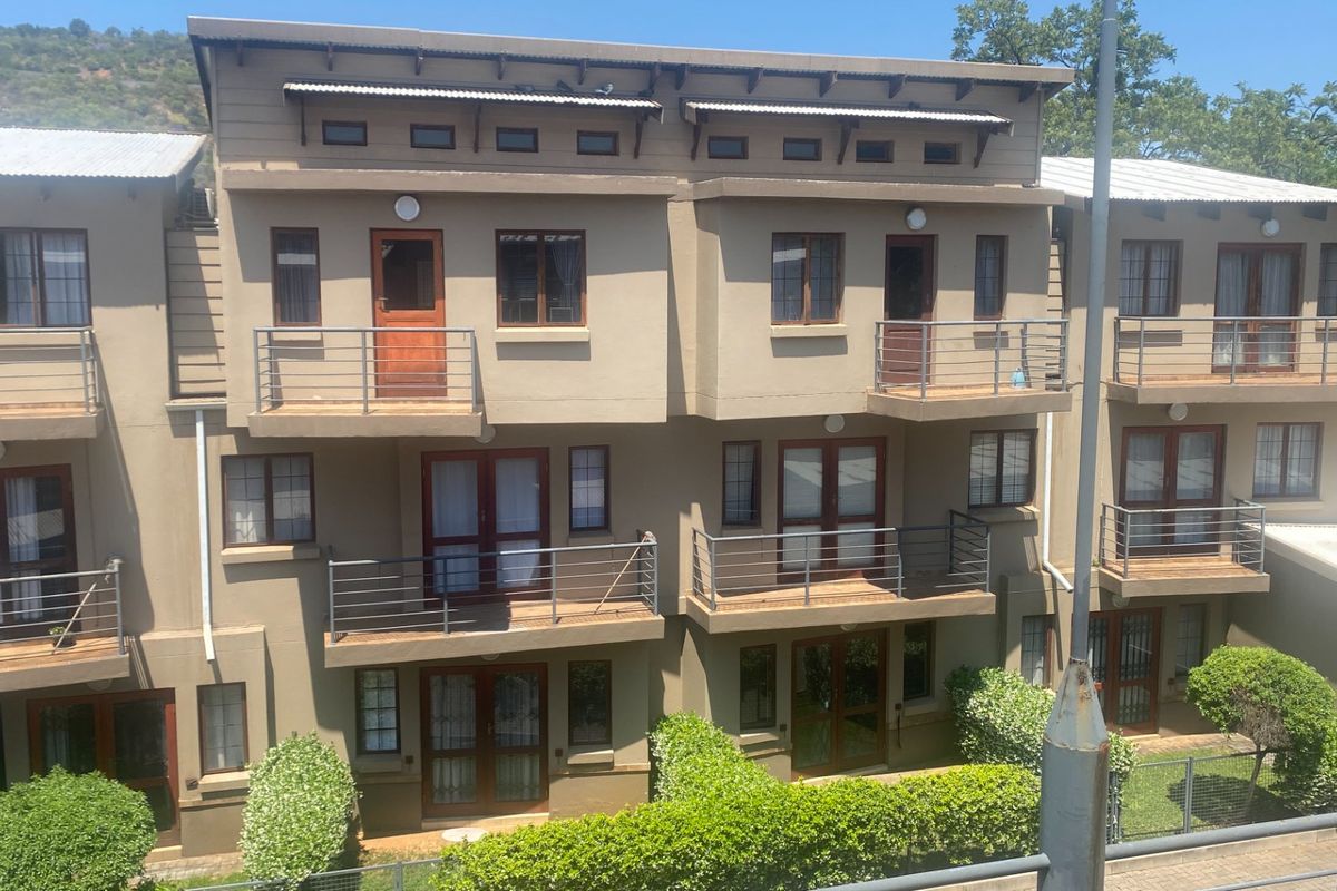 Rear elevation of a multi-story apartment complex featuring private balconies with metal railings and timber-framed doors and windows.