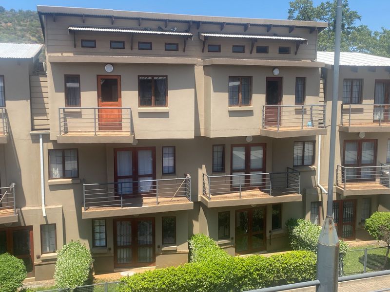 Rear elevation of a multi-story apartment complex featuring private balconies with metal railings and timber-framed doors and windows.