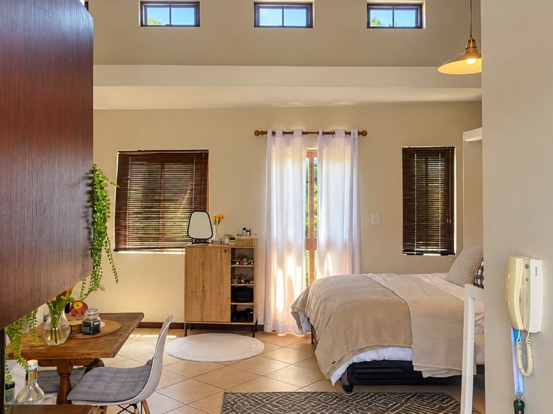 A well-lit bedroom featuring tiled flooring, clerestory windows for natural light, and an integrated intercom system.