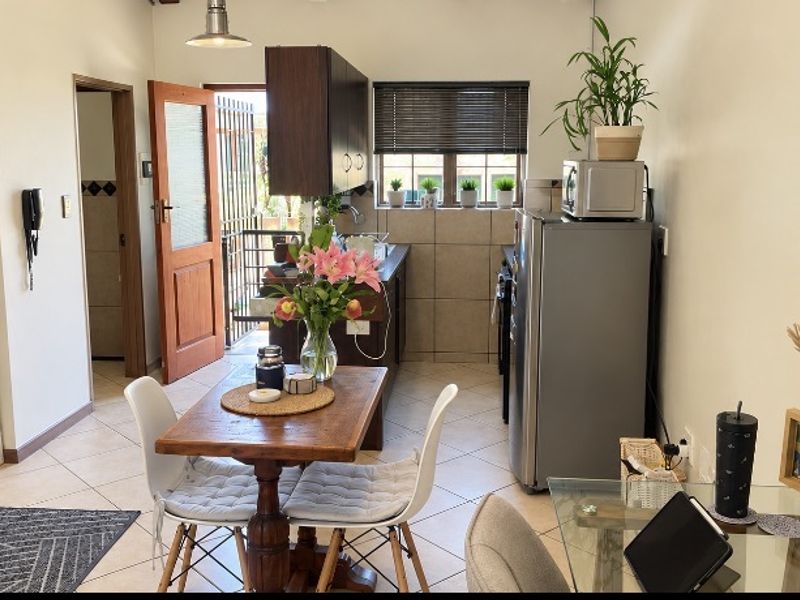 Open plan living and kitchen area featuring tiled flooring, built-in cabinetry, and direct access to an outdoor space through a timber door.