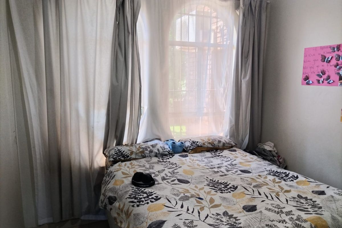 A bedroom featuring an arched window with security bars and decorative cornice detailing.