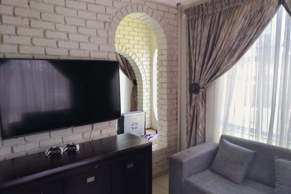 Living room featuring a distinctive white painted exposed brick wall with an arched architectural detail and large window with curtains.