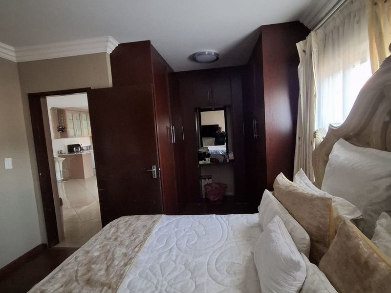 A bedroom featuring dark wood built-in cupboards, crown molding, and a view into an adjacent kitchen area.