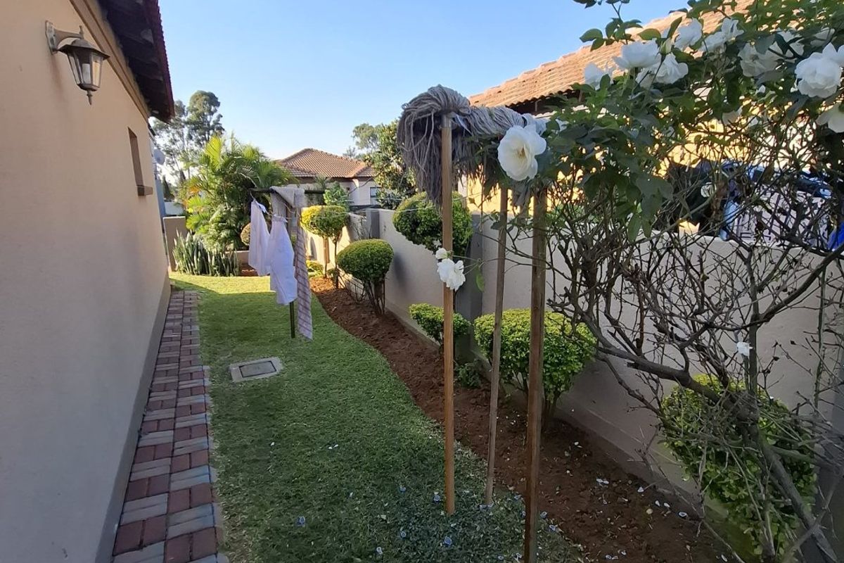 A side garden area featuring a paved walkway, lawn, and boundary wall, providing a functional outdoor space along the side of the property.