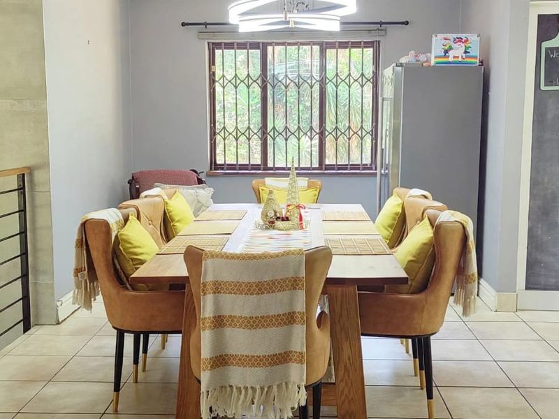 A dining area featuring tiled flooring, a window with security bars, and a unique chalkboard door, providing a functional space for family meals.