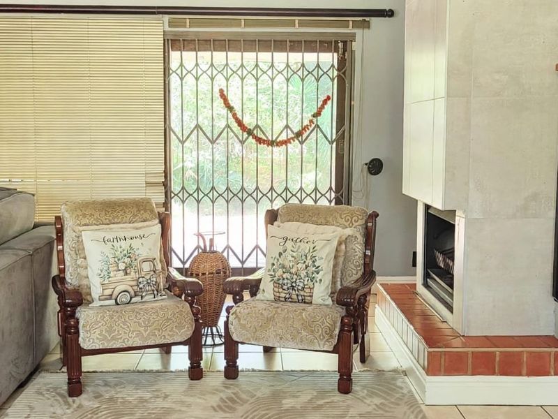A living room featuring a built-in fireplace with a tiled hearth, security gate access to the exterior, and a staircase railing.