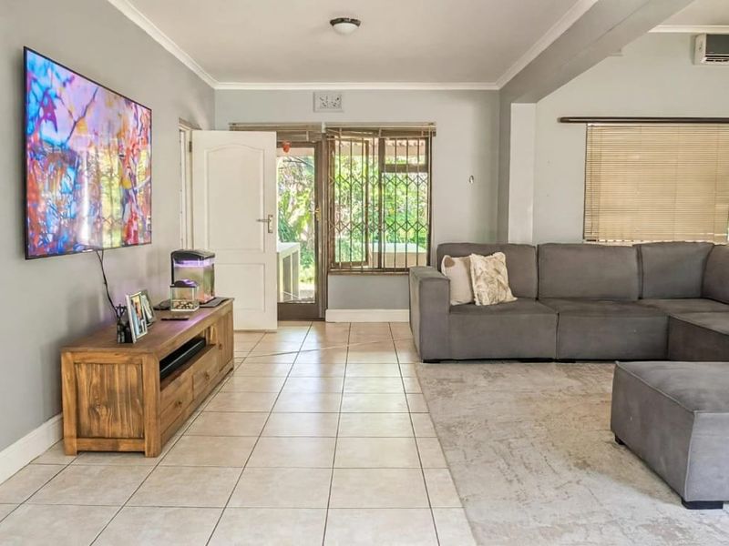 Spacious living room featuring tiled flooring, a wall-mounted air conditioning unit, and direct access to the exterior through a secure door.