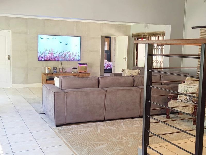 Spacious open-plan living area featuring tiled flooring, a modern feature wall, and a contemporary metal balustrade overlooking the lower level.