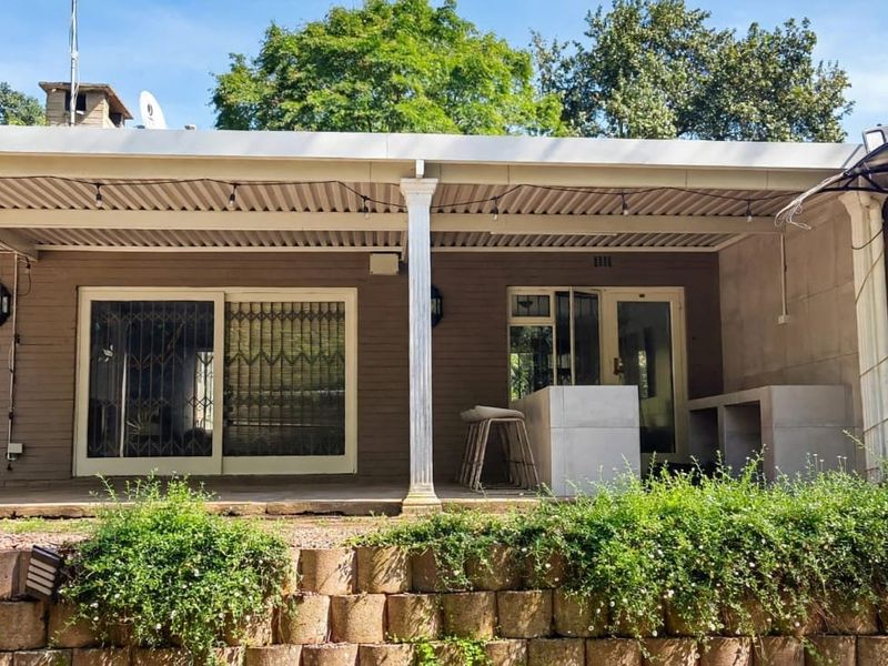 Covered outdoor patio featuring a built-in braai, concrete prep counter, and direct access to the home through sliding security doors.
