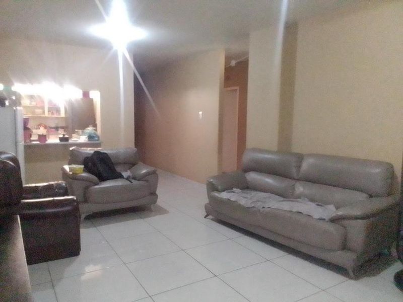 An open-plan living area featuring tiled flooring and a kitchen pass-through, providing a functional layout for the apartment.