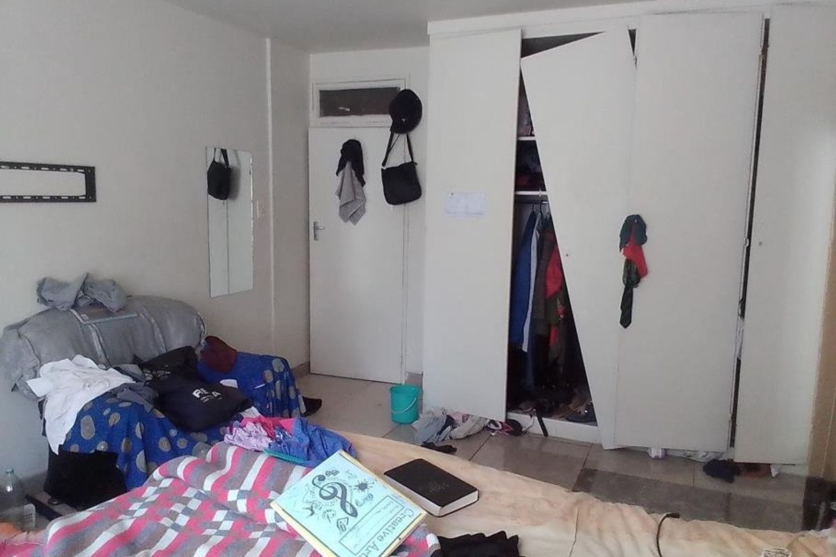 A bedroom featuring a built-in wardrobe with a damaged door, requiring repair or replacement to restore functionality.