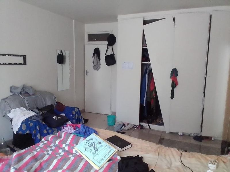 A bedroom featuring a built-in wardrobe with a damaged door, requiring repair or replacement to restore functionality.