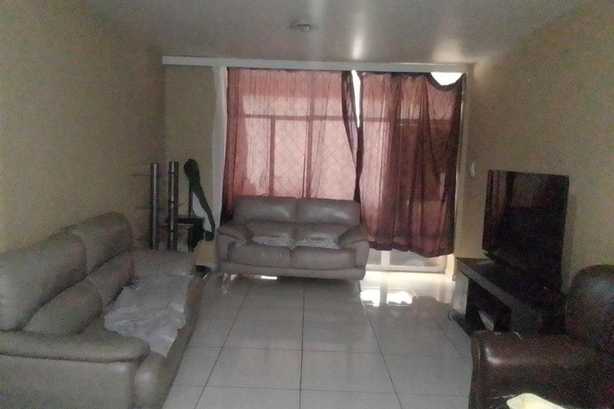 A living room featuring large format floor tiles and a sliding glass door providing natural light.