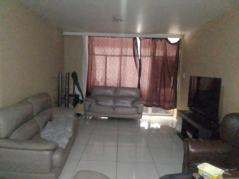A living room featuring large format floor tiles and a sliding glass door providing natural light.