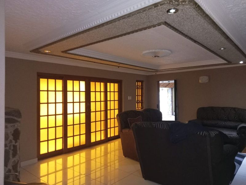 Spacious living room featuring tiled flooring, a decorative recessed ceiling with downlights, and large sliding glass doors providing natural light.