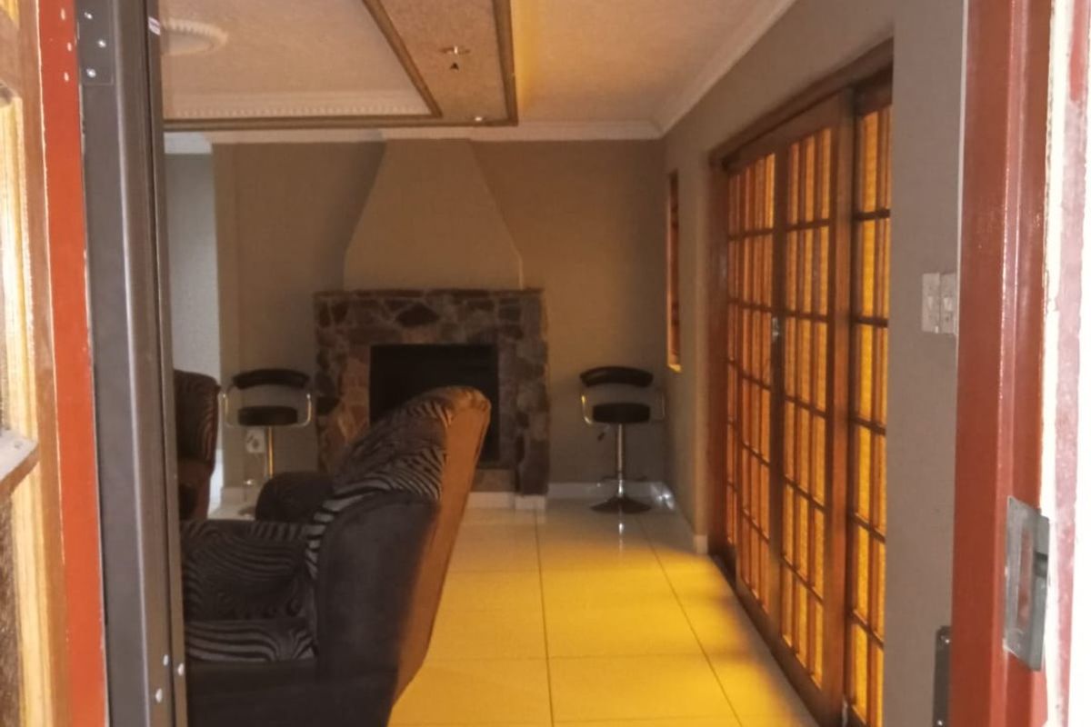 A living room featuring a stone fireplace, tiled flooring, and large wooden sliding doors leading to an outdoor area.
