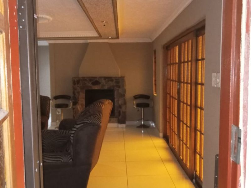 A living room featuring a stone fireplace, tiled flooring, and large wooden sliding doors leading to an outdoor area.