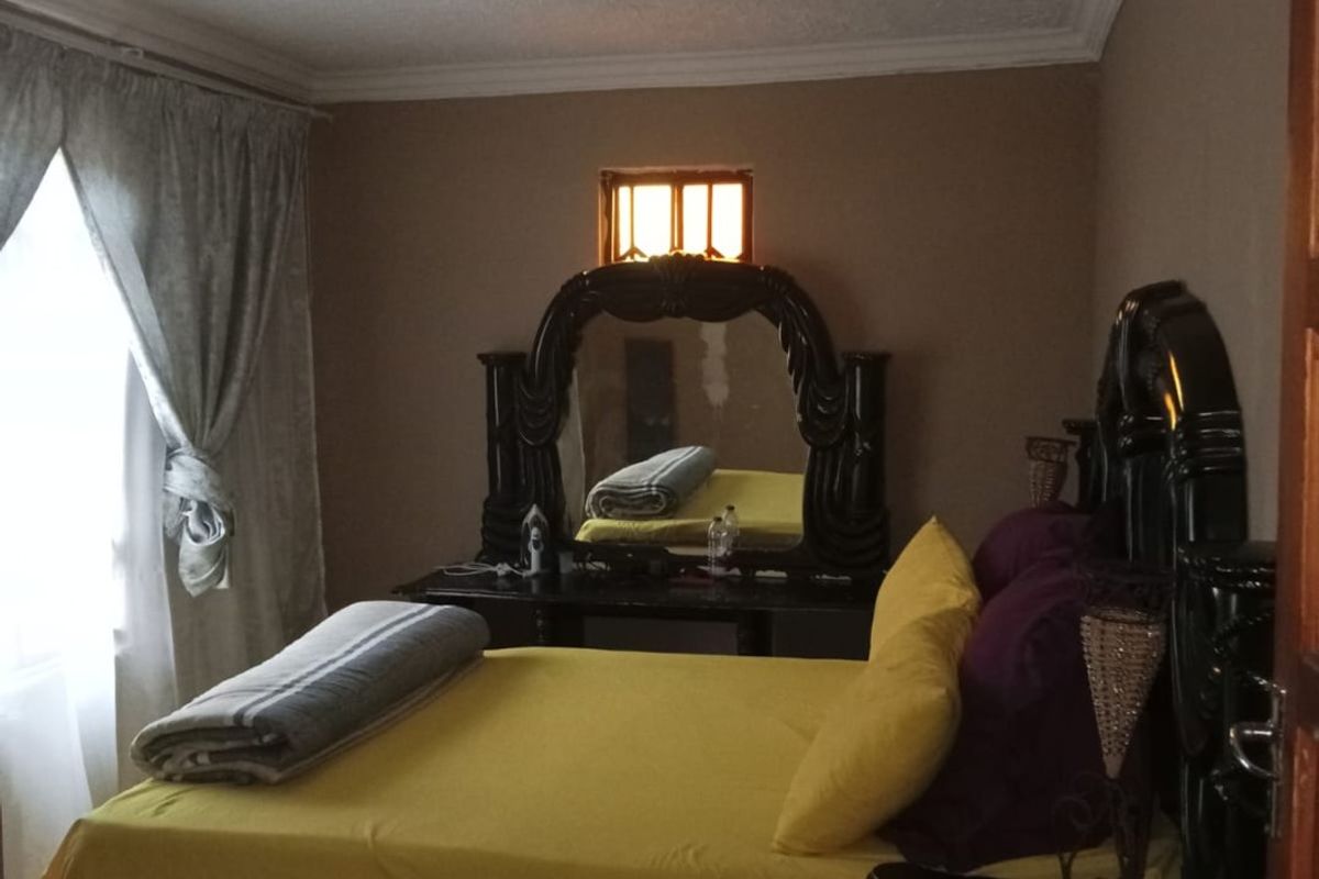 A bedroom featuring neutral wall tones, ceiling cornicing, and a small high-level window providing natural light.