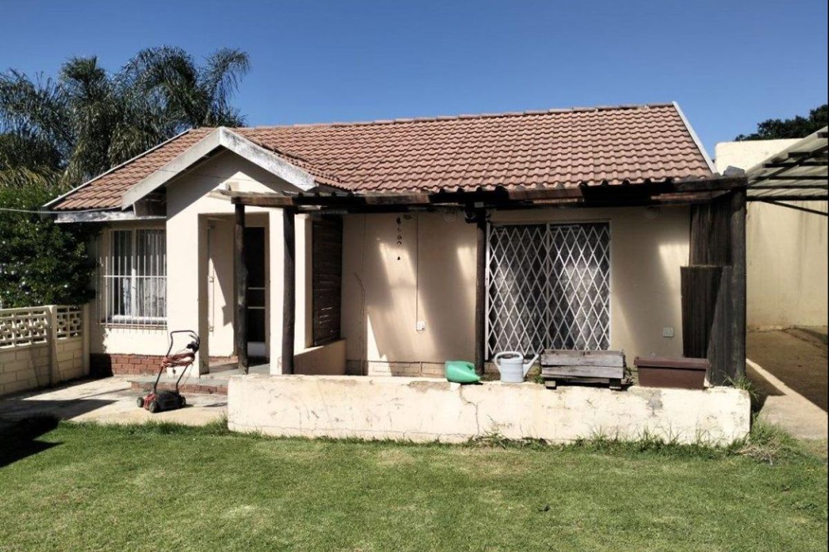 Rear view of the house featuring a tiled roof, a covered patio area with a timber pergola, and a small garden space.