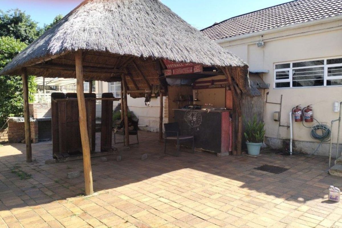 Outdoor entertainment area featuring a thatched lapa with a built-in bar and brick-paved patio space, ideal for social gatherings.