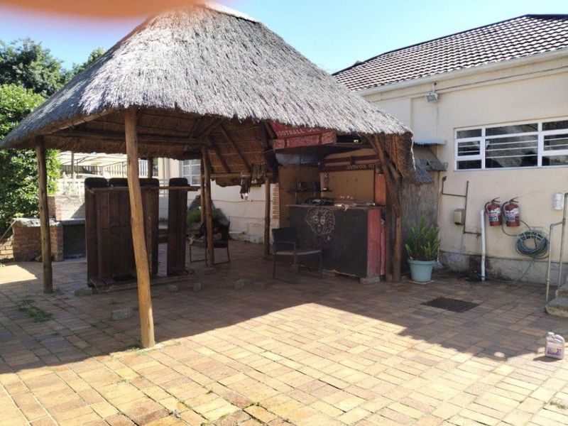 Outdoor entertainment area featuring a thatched lapa with a built-in bar and brick-paved patio space, ideal for social gatherings.
