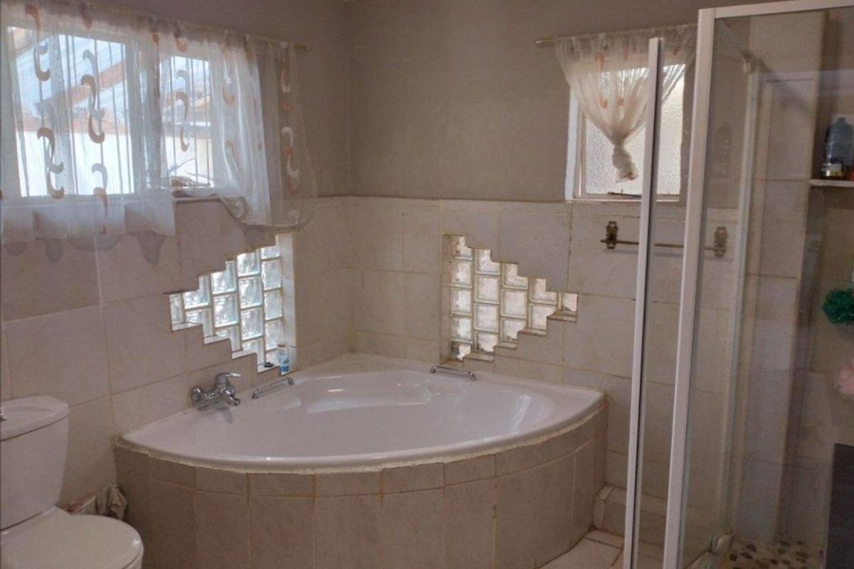 A functional bathroom featuring a corner bathtub, a separate glass shower enclosure, and decorative glass block wall inserts.