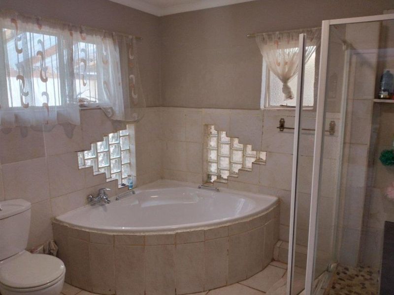 A functional bathroom featuring a corner bathtub, a separate glass shower enclosure, and decorative glass block wall inserts.