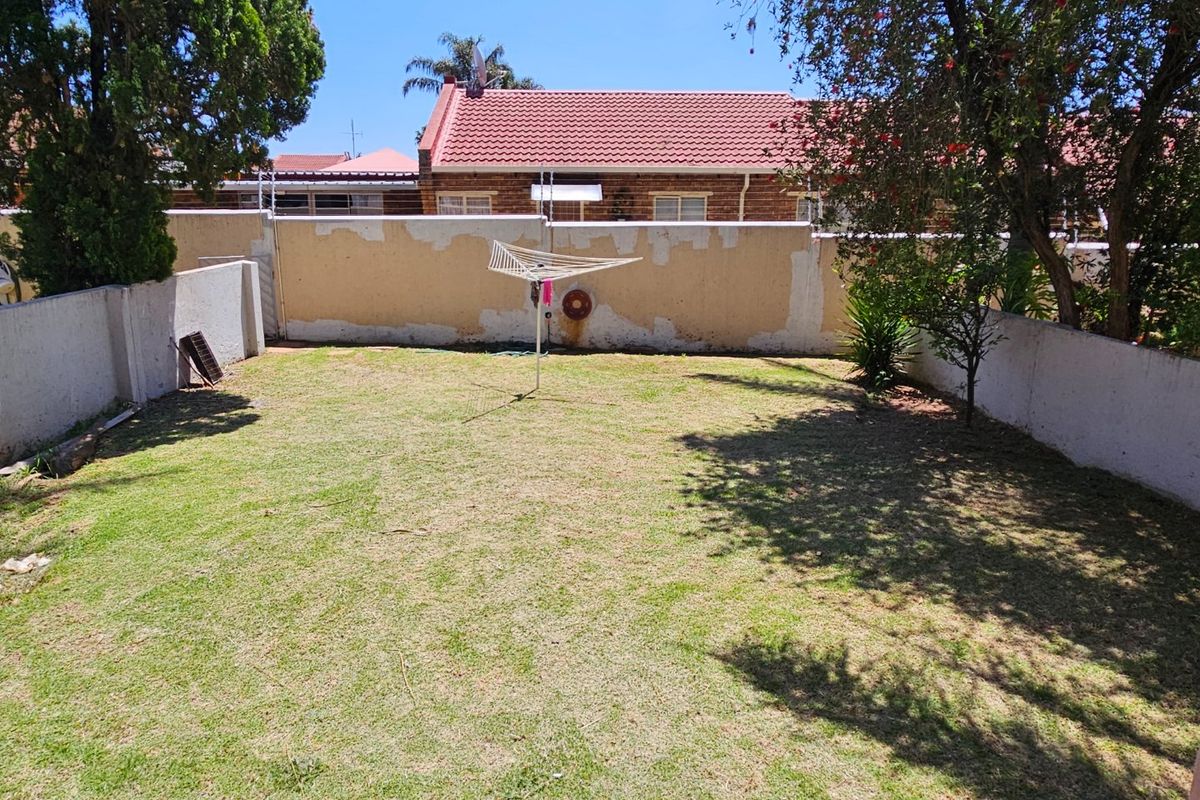 A private rear garden featuring a lawn area enclosed by perimeter walls with integrated electric fencing.