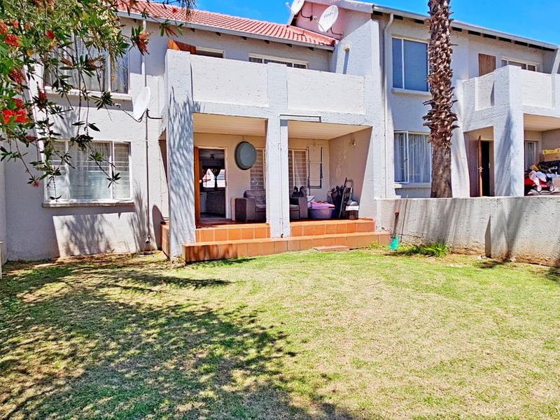 Rear view of the apartment complex featuring a private garden area and a covered patio with terracotta tiling.