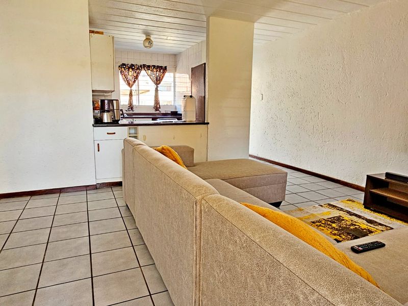 Open plan living area featuring tiled flooring and a compact kitchen with built-in cabinetry and sink.