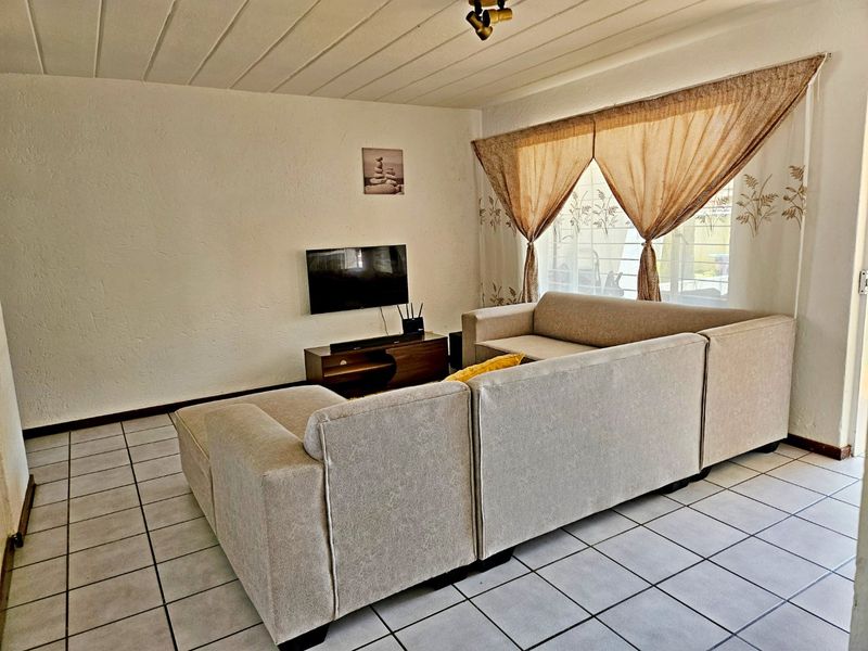 A living room featuring tiled flooring and a textured ceiling, providing a functional and neutral space for relaxation.