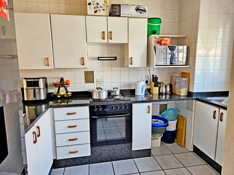 A functional kitchen featuring white cabinetry, granite countertops, a built-in oven, and tiled finishes throughout.