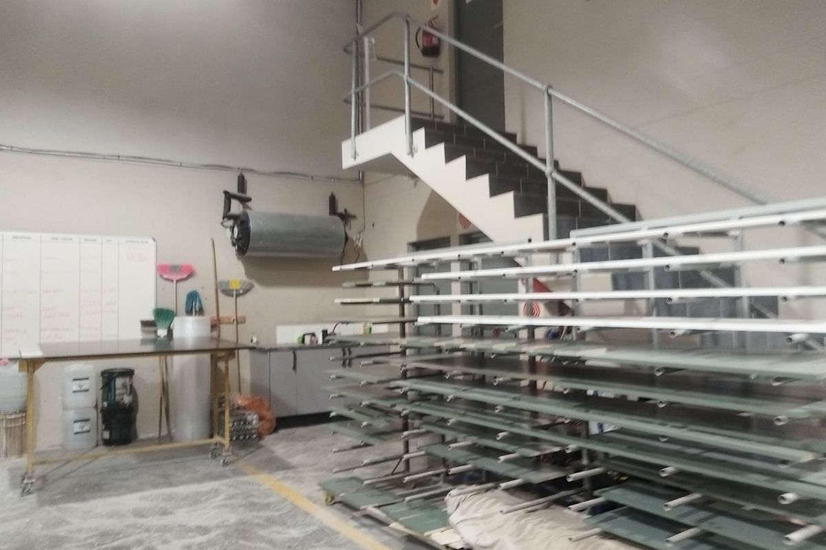 Industrial utility space featuring a concrete floor, metal staircase with handrails, and wall-mounted water heater, suitable for workshop or storage operations.
