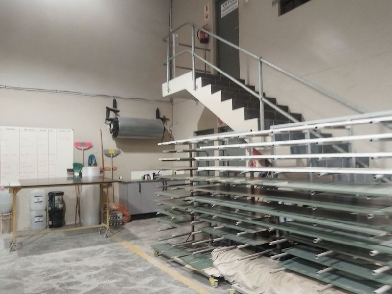 Industrial utility space featuring a concrete floor, metal staircase with handrails, and wall-mounted water heater, suitable for workshop or storage operations.