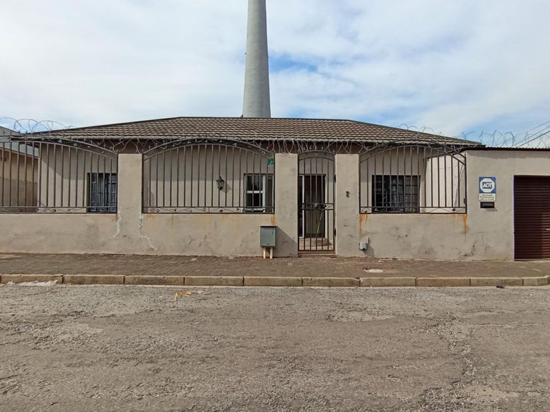 Front elevation of a single-story house featuring a tiled roof, security fencing with razor wire, and an integrated roller shutter garage door.