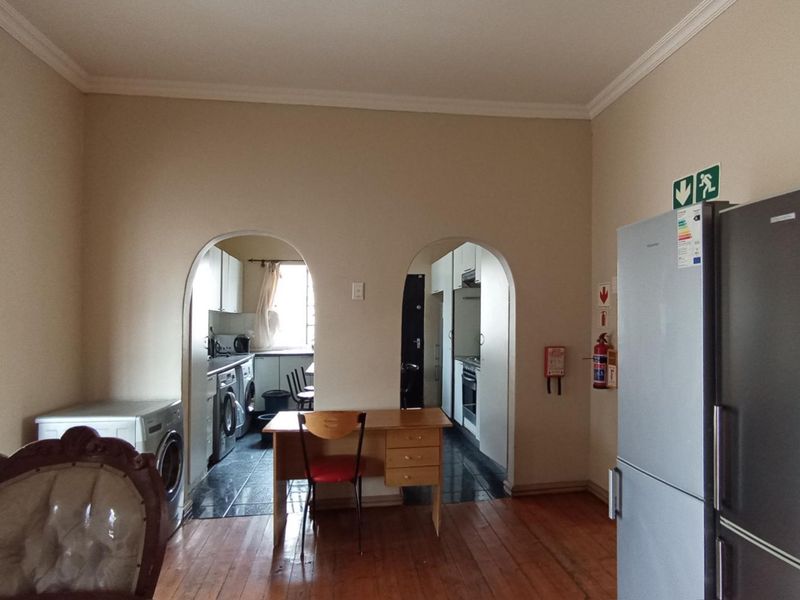 A functional scullery and utility area featuring dual archway access, hardwood flooring, and integrated utility connections for laundry and kitchen preparation.