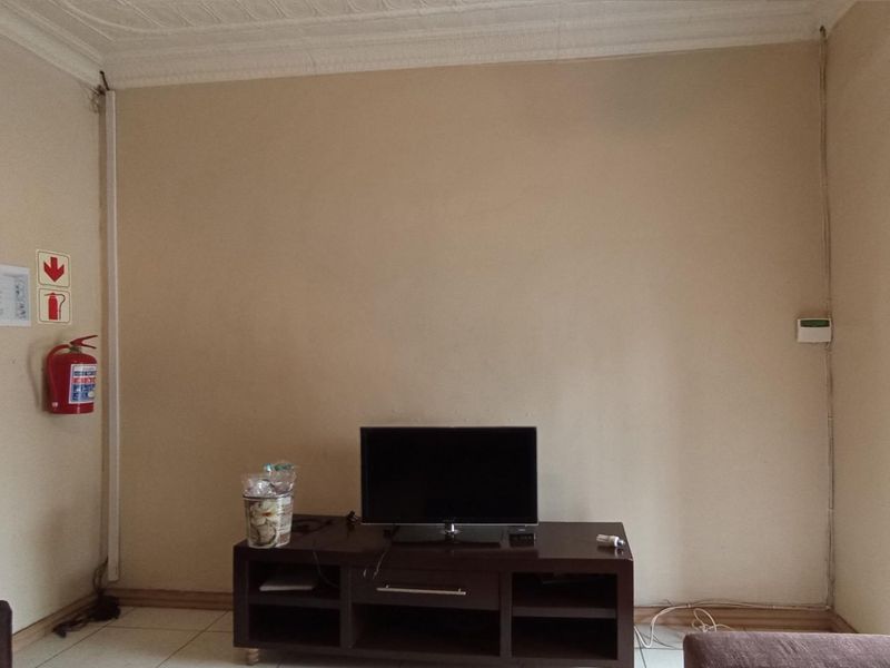 A living room area featuring arched doorways, decorative ceiling cornices, and tiled flooring, currently showing visible surface-mounted electrical wiring.