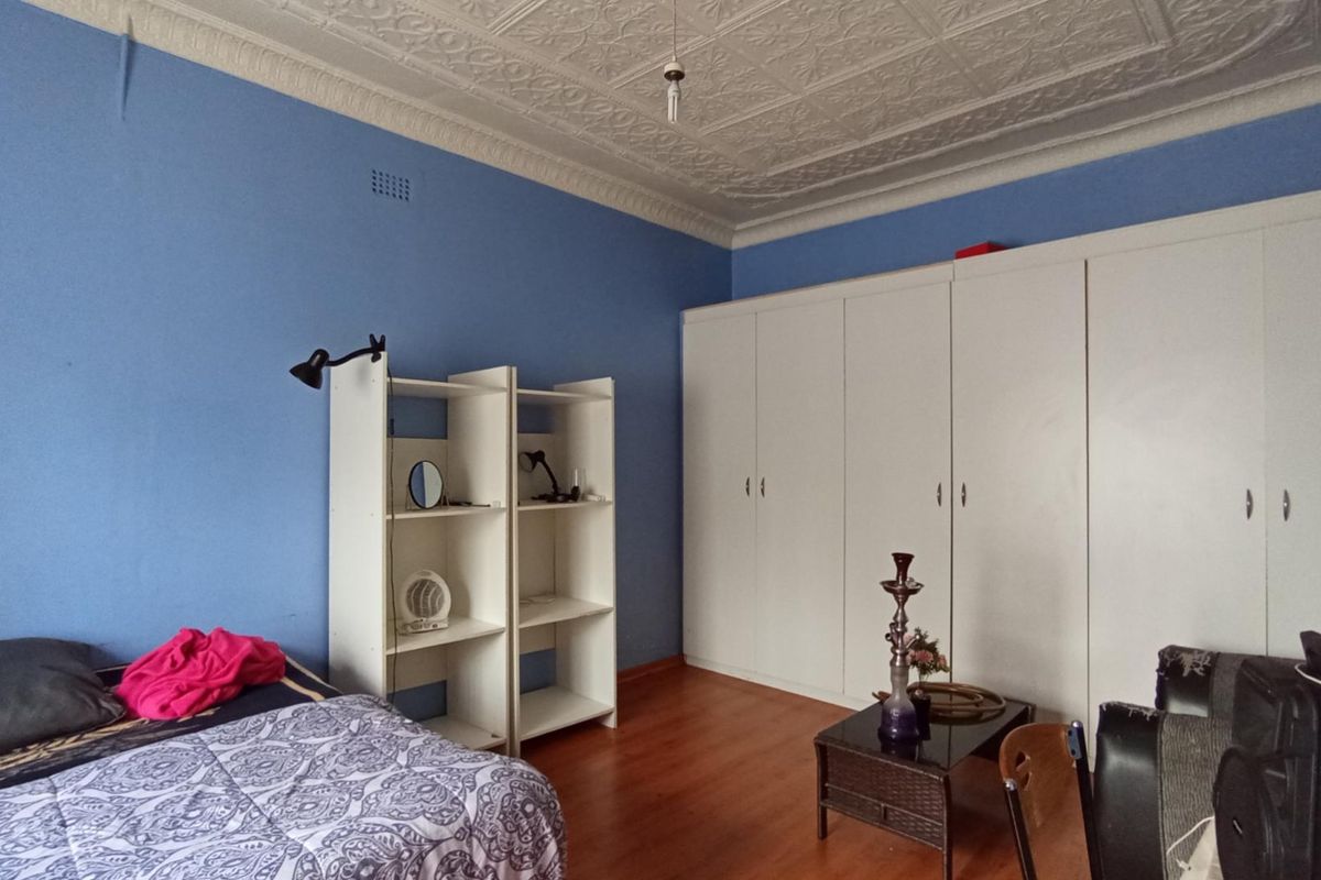 Bedroom featuring a classic ornate pressed metal ceiling, laminate flooring, and extensive built-in wardrobe storage.