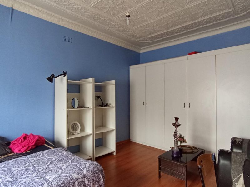 Bedroom featuring a classic ornate pressed metal ceiling, laminate flooring, and extensive built-in wardrobe storage.