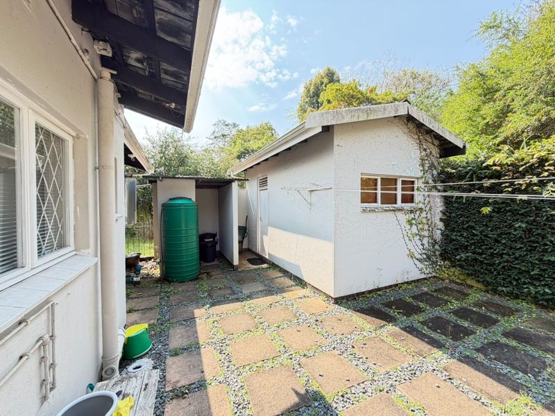 Rear courtyard area featuring a paved surface, a water tank, and a detached outbuilding with visible exterior wear.