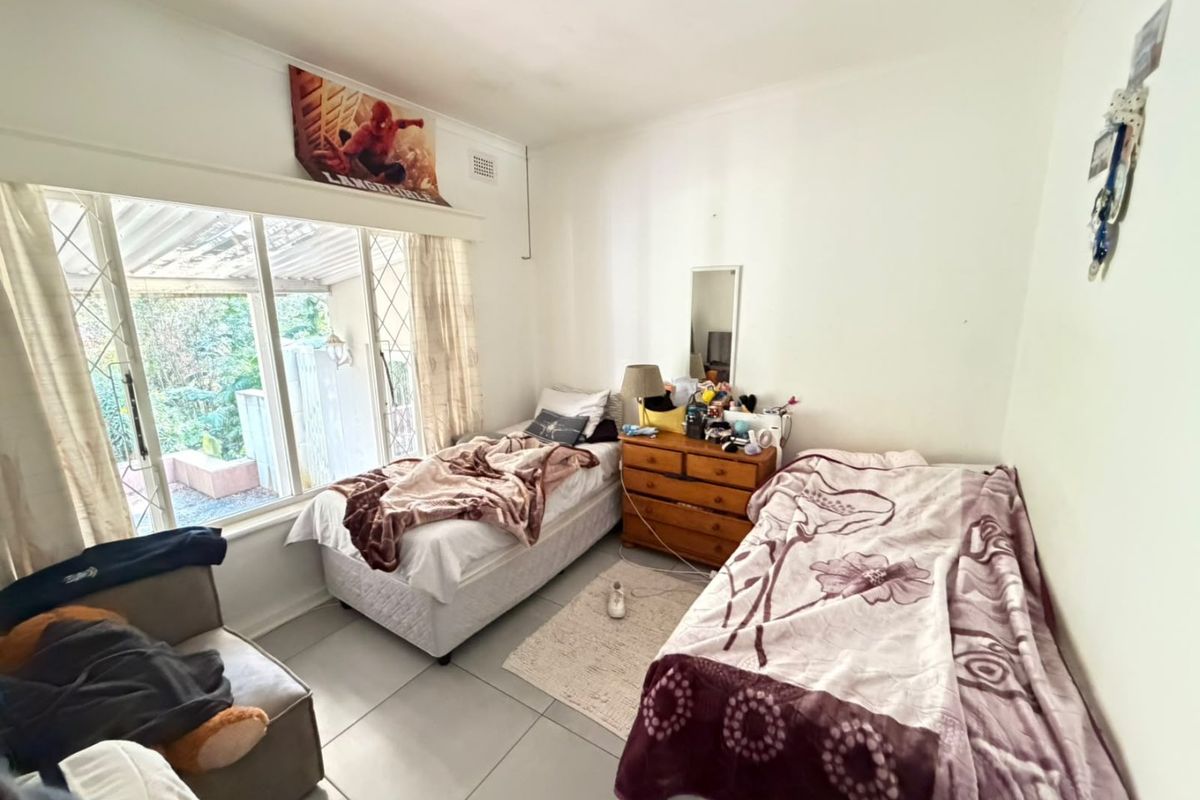 A bedroom featuring tiled flooring and a large sliding glass door providing access to the outdoor area.