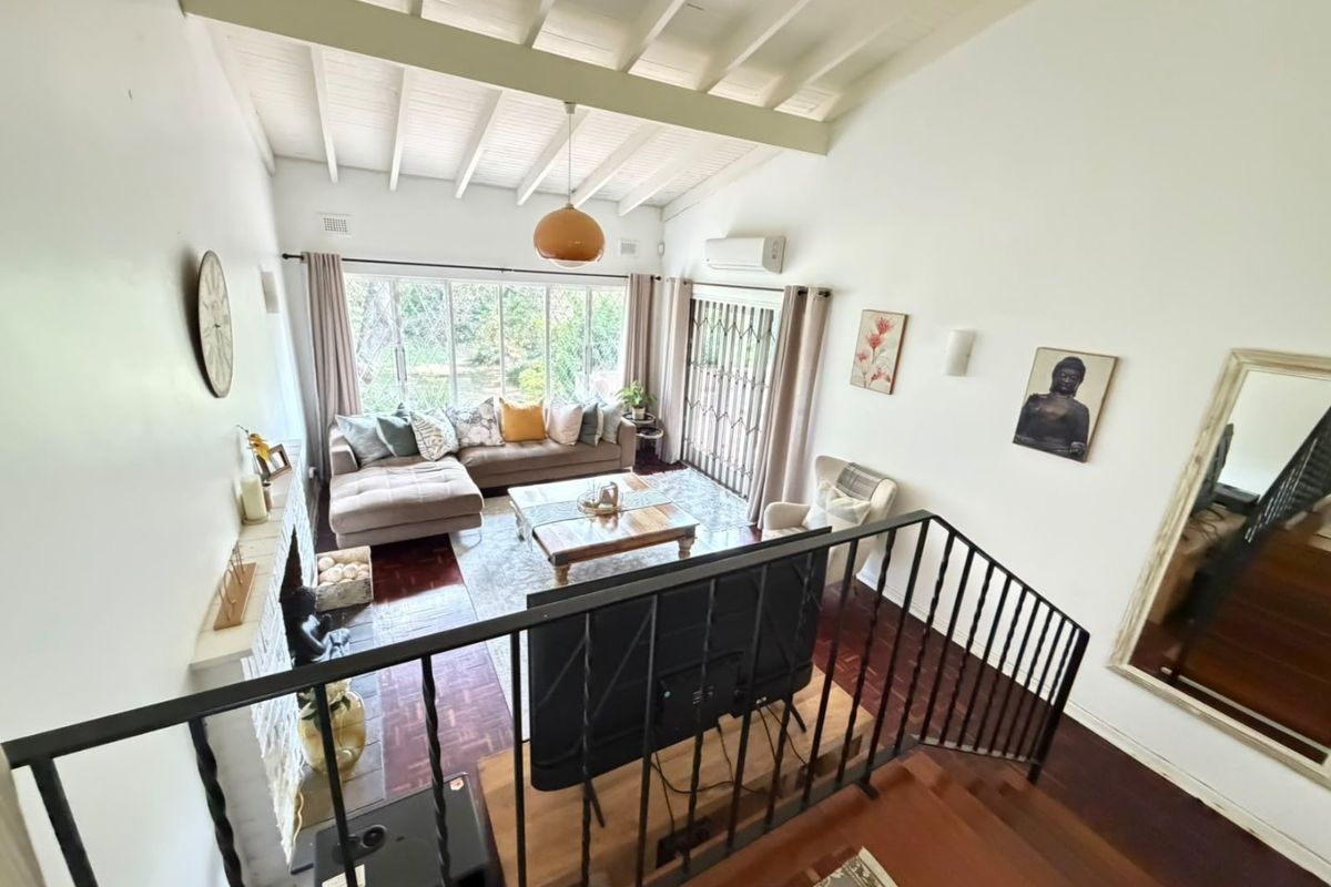Spacious living room featuring high exposed beam ceilings, parquet flooring, a fireplace, and large windows providing ample natural light and garden views.
